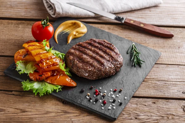 Burger grill with vegetables and sauce on a wooden surface