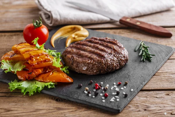 Grelha de hambúrguer com legumes e molho em uma superfície de madeira — Fotografia de Stock