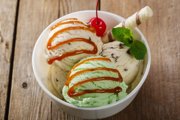 บอลพิสตาชิโอและไอศกรีมขาวในชามกับคาราเมล — ภาพถ่ายสต็อก