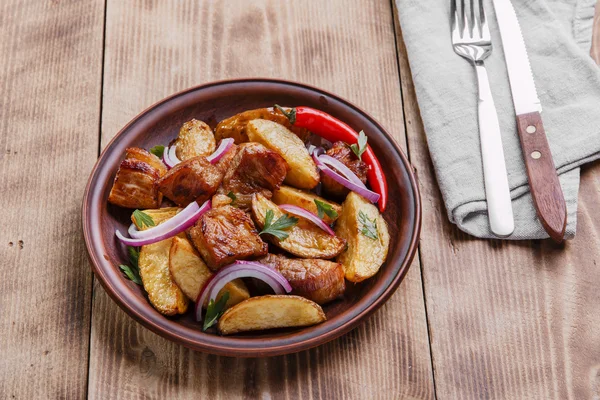 Gebakken gebakken aardappelen met vlees plaat op houten oppervlak — Stockfoto