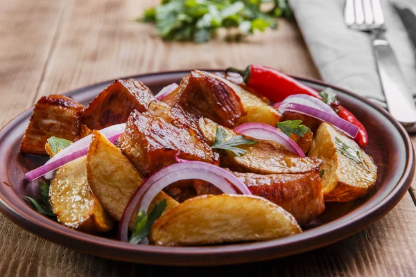 Gebakken gebakken aardappelen met vlees plaat op houten oppervlak — Stockfoto