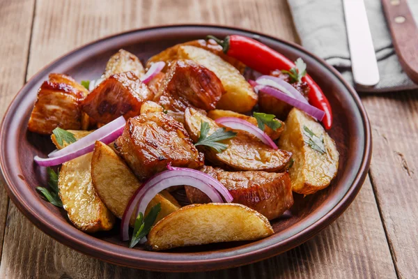 Batatas fritas assadas com placa de carne na superfície de madeira — Fotografia de Stock