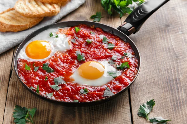 Fried eggs in tomato sauce in the pan — Stock Photo, Image