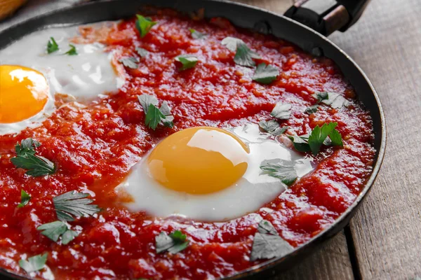 Fried eggs in tomato sauce in the pan — Stock Photo, Image
