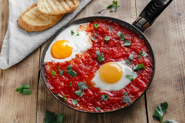 Fried eggs in tomato sauce in the pan — Stock Photo, Image