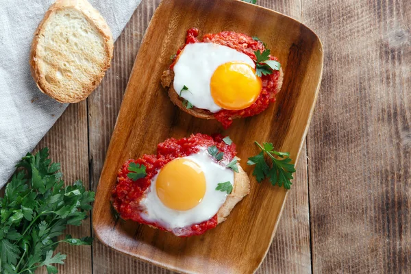 Fried eggs with tomato sauce on bruschetta — Stock Photo, Image