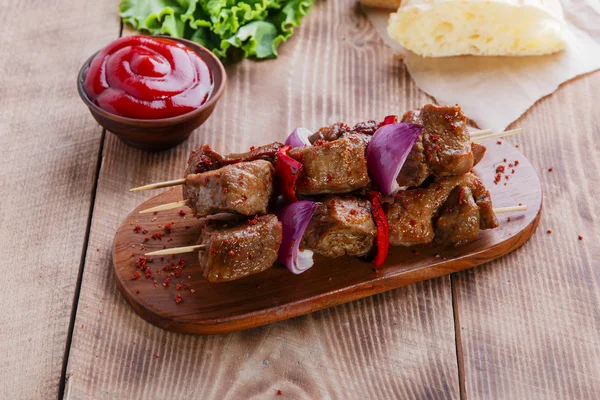 Brochetas kebab de carne con salsa roja en el tablero — Foto de Stock