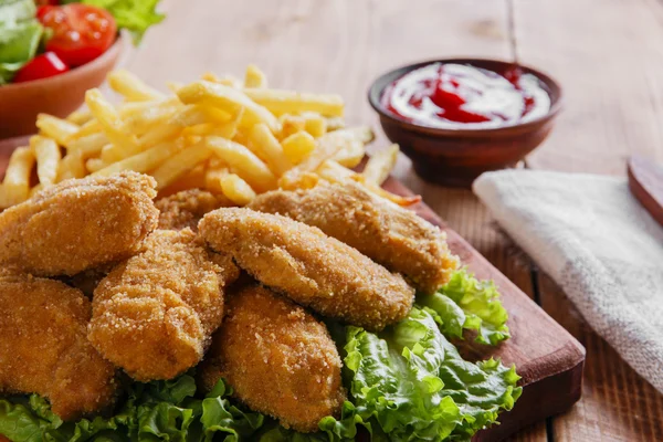 Kippenvleugels, gebakken in paneermeel met saus en frietjes — Stockfoto