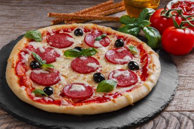 Salam domates ve peynir siyah bir taş üzerinde pizza