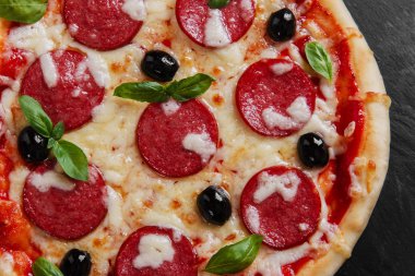 Salam domates ve peynir siyah bir taş üzerinde pizza