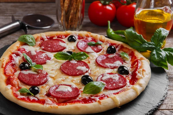 Pizza com tomate de salame e queijo em uma pedra preta — Fotografia de Stock