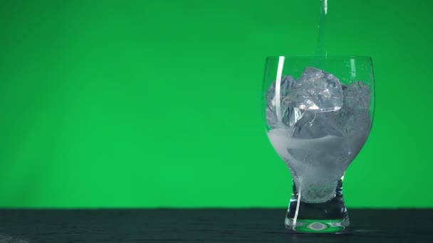 Nalije šumivou vodu do skleněného poháru s kousky ledu. — Stock video