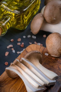 Taze çiğ kral, kraliyet istiridye mantarları koyu ahşap masada, dilimlenmiş, hazırlanma, üst manzara