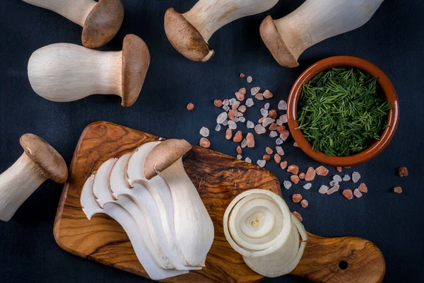 Taze çiğ kral, kraliyet istiridye mantarları koyu ahşap masada, dilimlenmiş, hazırlanma, üst manzara