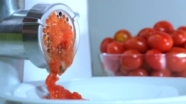 Domatesler bükülmüş Domates, domates ezmesini hazırlamak için öğütücüye sokulur. Domates ezmesini hazırlamak için bir et öğütücü.