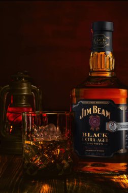 Bir şişe Jim Beam Black Extra Aged Bourbon viski ve buzlu kırmızı zemin.