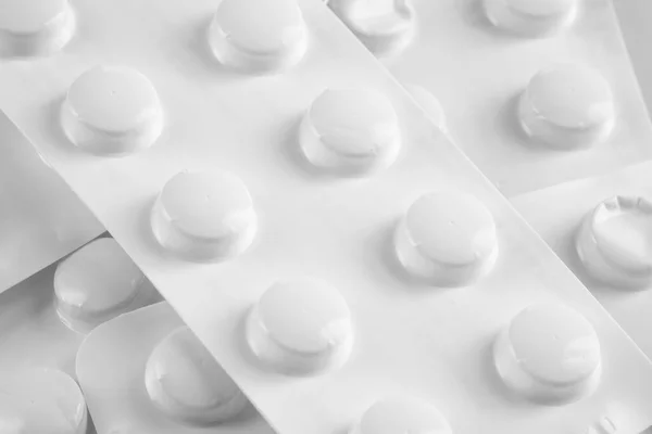 Pílulas brancas em blister branco no fundo branco — Fotografia de Stock