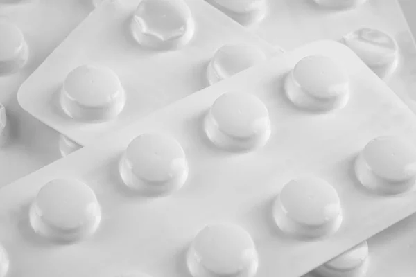 Pílulas brancas em blister branco no fundo branco — Fotografia de Stock