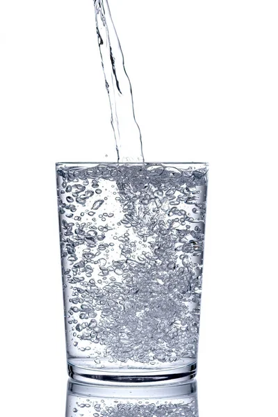 Zamknąć wlewanie oczyszczonej świeżej wody z butelki w szklance. — Zdjęcie stockowe