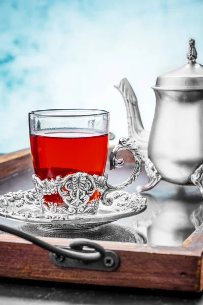 Silver teapot with a cup fruit tea in a cup holder on a mirror tray — Foto de Stock