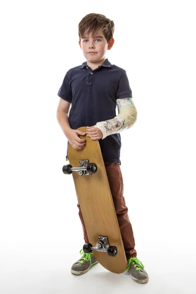 Söt ung pojke håller en skateboard — Stockfoto