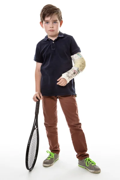 Pojke med gjutna på vänster arm och tennisracket — Stockfoto