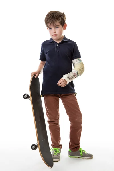 Söt ung pojke håller en skateboard — Stockfoto