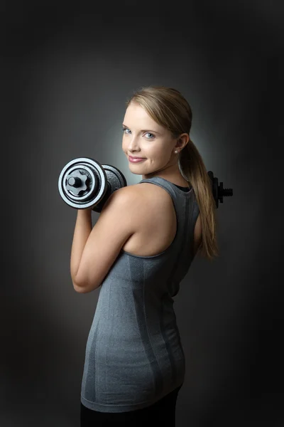 Sportliche Frau auf grauem Hintergrund mit Hanteln — Stockfoto