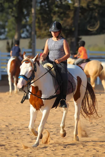 Adolescente menina está montando um cavalo — Fotografia de Stock