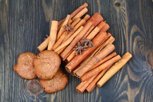 Cinnamon sticks with star anise and cookies on wooden table — Stock Photo, Image