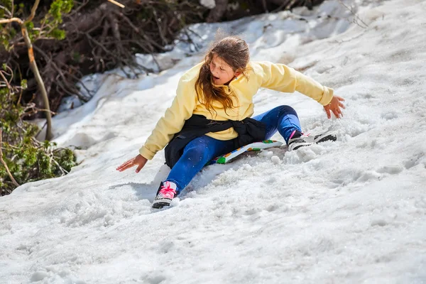 雪の山からの少女のスライドは — ストック写真