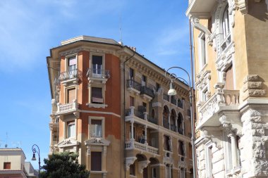 Roma, İtalya - 19 Eylül 2025: Roma 'nın eşsiz Copped bölgesinde canlı köşe binası. Özenle hazırlanmış balkonları, dekoratif cepheleri ve mavi gökyüzünün altında terasotta renklerini barındıran İtalyan mimarisi.
