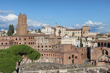 Roma, İtalya - 21 Eylül 2025: Trajan 'ın Roma, İtalya' daki harabelerinin çarpıcı bir manzarası, ortaçağ ve modern binaların mavi gökyüzü altında yükselmesi.