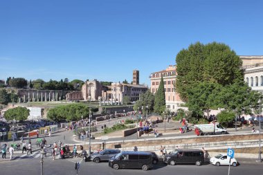 Roma, İtalya - 21 Eylül 2025: Roma, İtalya 'da modern trafik ve yayaların güneşli bir günde antik Roma Forumu kalıntıları ve tarihi binaların önünden geçtiği yoğun bir caddenin yüksek açılı görüntüsü.