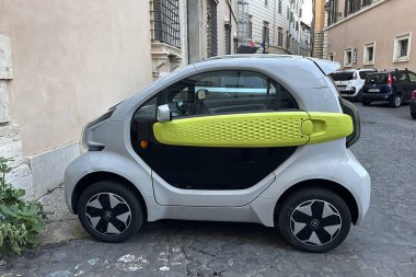 Roma, İtalya - 17 Eylül 2025: gri XEV Yoyo elektrikli mikroarabası Roma 'da bir kaldırım taşı caddesinde park edilmiş. Kireç yeşili aksanlı ve 3 boyutlu baskılı sıkıştırılmış İtalyan EV tasarımı. Tarihi bir Avrupa şehrinde sürdürülebilir kentsel hareketlilik. Modern şehir tranı