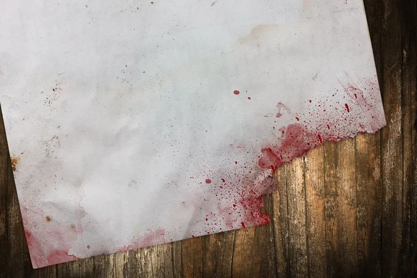 Torn old paper with blood stains on a wooden background — Stock Photo, Image