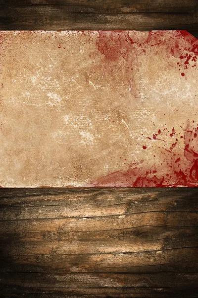 Dark old paper with blood stains on a wooden background — Stock Photo, Image