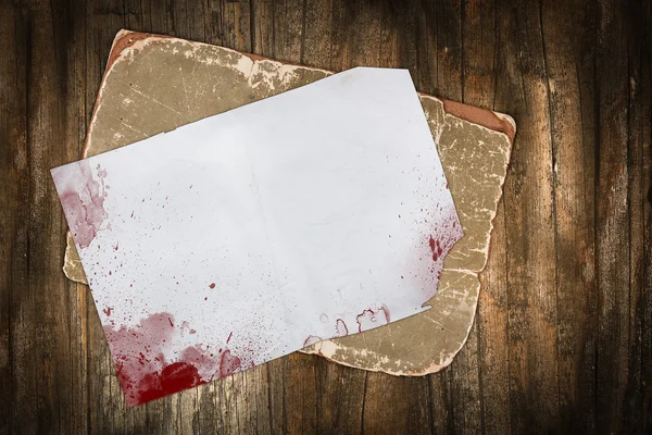 Papéis antigos com manchas vermelhas de sangue em um fundo de madeira escura — Fotografia de Stock