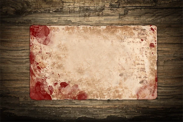 Papel velho com manchas de sangue em um fundo de madeira — Fotografia de Stock