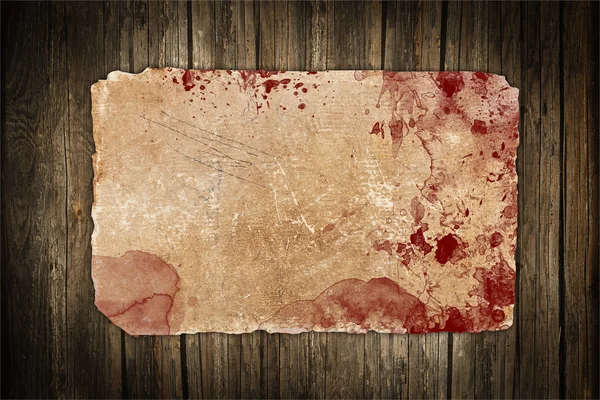 Faded old paper with red blood stains on a wooden background — Stock Photo, Image