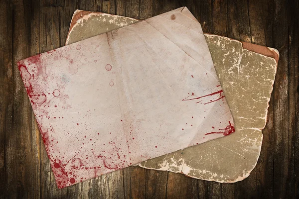 Wrinkled old paper with blood spots on a wooden background Royalty Free Stock Photos