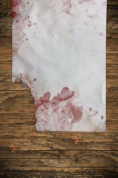 Hoja de papel dañada cubierta con sangre en madera —  Fotos de Stock