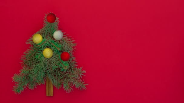 Stoppa rörelse animation av julgran med dekorationer på röd bakgrund, — Stockvideo