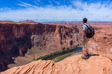 Horseshoe Bend 'de yürüyüşçü. Horseshoe Bend, Amerika Birleşik Devletleri 'nin Arizona eyaletinin Page kasabası yakınlarında yer alan Colorado Nehri' nin at nalı şeklinde kesilen bir koludur.