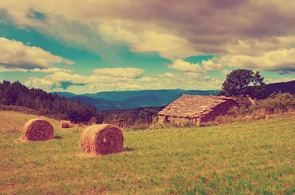 Paesaggio con balle raccolte e casa in pietra — Foto Stock