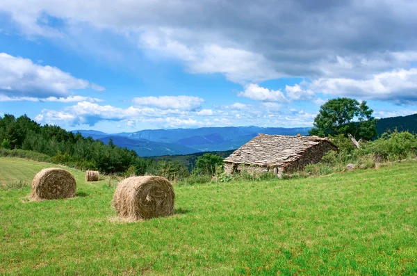 Paesaggio con balle raccolte e casa in pietra — Foto Stock