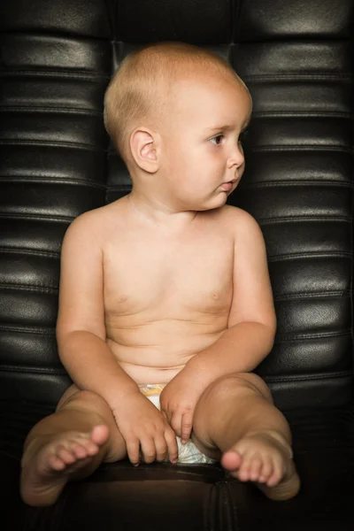 Niño desnudo en una silla de cuero — Foto de Stock