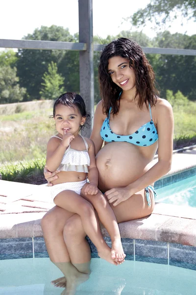 Mujer embarazada junto a la piscina con su hija pequeña (2 ) —  Fotos de Stock