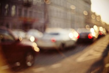 Bulanık, bulanık arka plan, gün batımında ulaşım yolu. Odak dışı şehir manzarası arabalarla dolu.