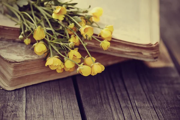 古い開いている本や木製のテーブルの上に黄色のバターカップの花束 — ストック写真